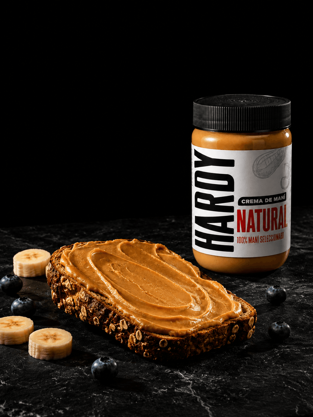Tostada integral con crema de maní Hardy, banana y arándanos sobre piedra negra